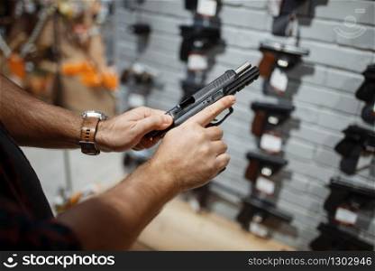Man choosing new handgun at showcase in gun shop. Male person buying pistol for security in weapon store, selfdefence and sport shooting hobby. Man choosing new handgun in gun shop