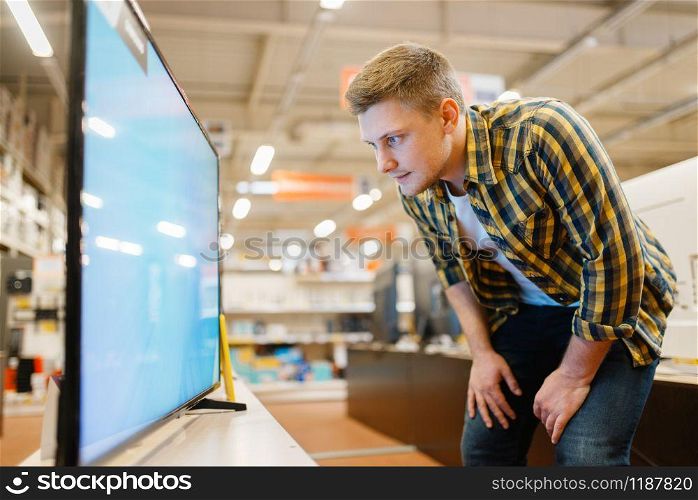 Man choosing TV in electronics store. Male person buying home electrical appliances in market. Man choosing TV in electronics store