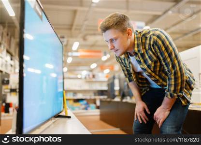 Man choosing TV in electronics store. Male person buying home electrical appliances in market. Man choosing TV in electronics store