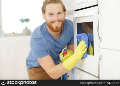 man cleaning oven in kitchen closeup