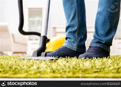 Man cleaning the floor carpet with a vacuum cleaner close up