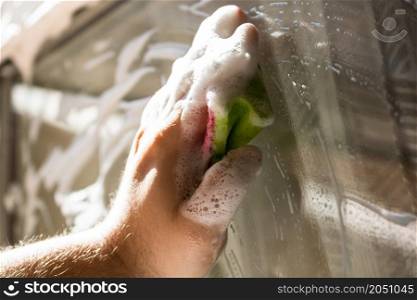 Man cleaning window using window cleaning squeegee and cleaning sprayer, cleaning services concept. Housework and housekeeping concept
