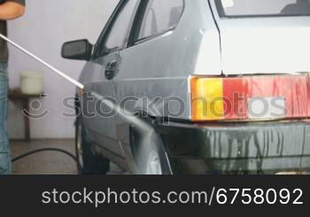 man cleans car with high pressure water jet