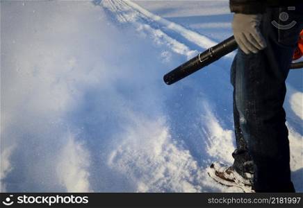Man cleans pavement from snow with blower