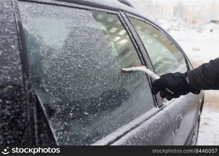 man cleans snow from car window