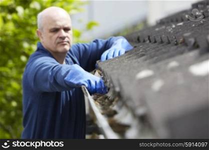 Man Clearing Leaves From Guttering Of House