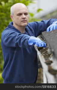 Man Clearing Leaves From Guttering Of House