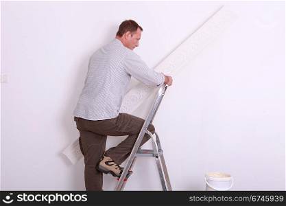 Man climbing ladder holding wallpaper