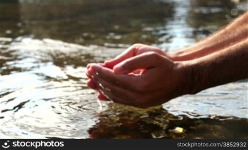 Man collecting water with both hands.Collecting water at the Mediterranean seashore.Removing clear water with hands.