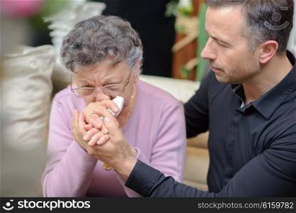 Man comforting weeping elderly lady