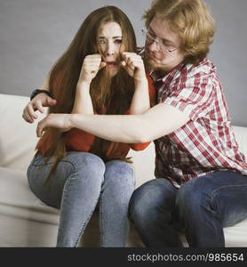 Man comforting woman sitting on sofa. Friend confiding to friend having a serious talk. Couple solving their love relationship problems.. Woman confiding to man on sofa
