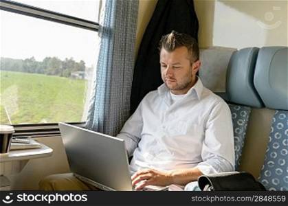 Man commuting with train using laptop travel serious typing internet