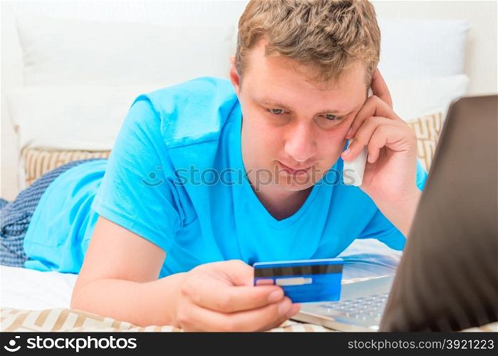 man consults by phone in his hand a credit card