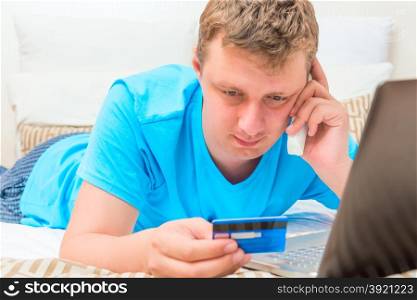 man consults by phone in his hand a credit card
