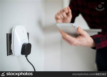 Man Controlling Smart Plug Using App On Mobile Phone