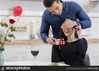 man covering his girlfriend s eyes before giving her gift