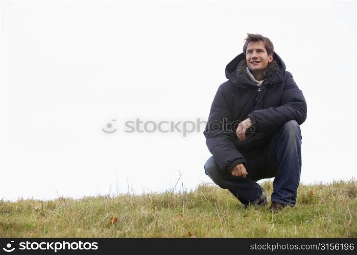 Man Crouching In Park