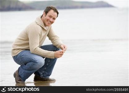 Man crouching on beach smiling