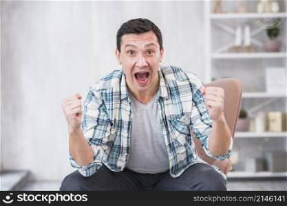 man crying showing fists chair home