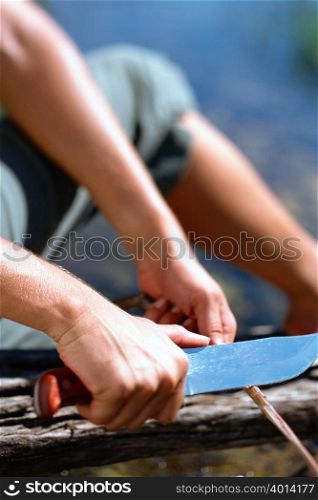 Man cutting a wooden stick