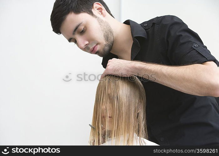 Man cutting a young womans hair in the hairdressers