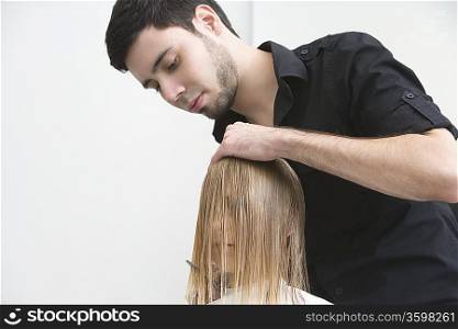 Man cutting a young womans hair in the hairdressers