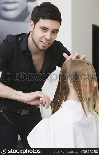 Man cutting and combing a young womans hair in the hairdressers