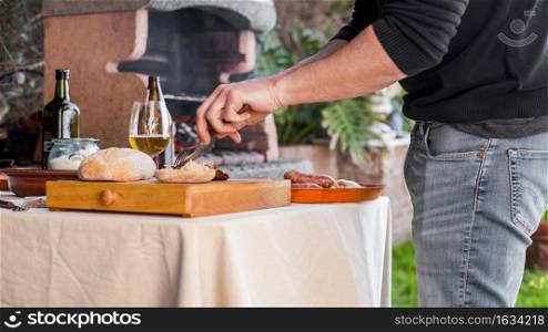 man cutting bread grilled chicken with fork knife outdoors