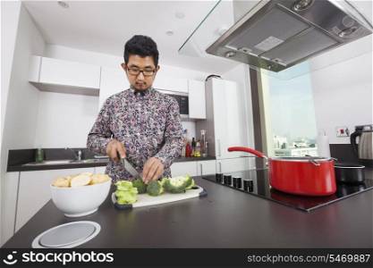 Man cutting broccoli at kitchen counter