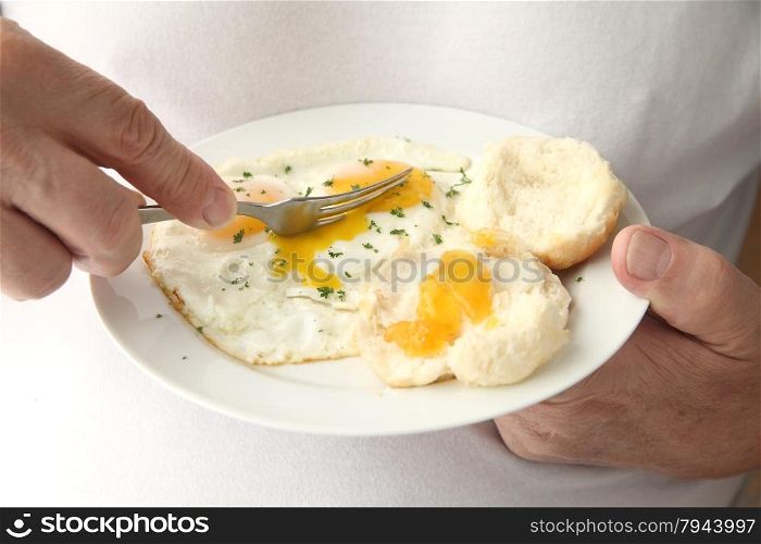 man cutting into fried eggs