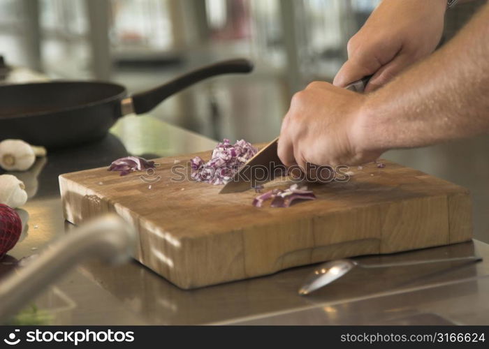 Man cutting the onions on a wooden board (shallow dof, some movement in the hands due to cutting)
