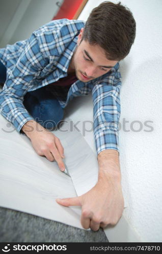 Man cutting underlay against skirting board