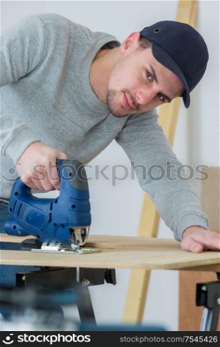 man cutting woodplank using bandsaw
