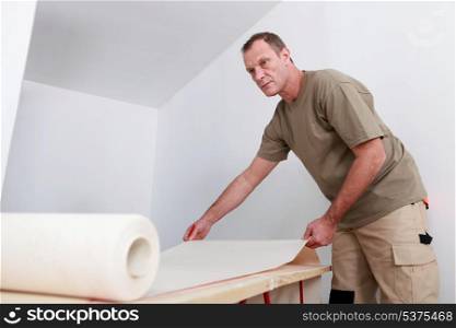 Man decorating apartment with new wallpaper