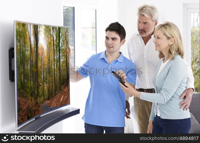 Man Demonstrating New Television To Mature Couple At Home