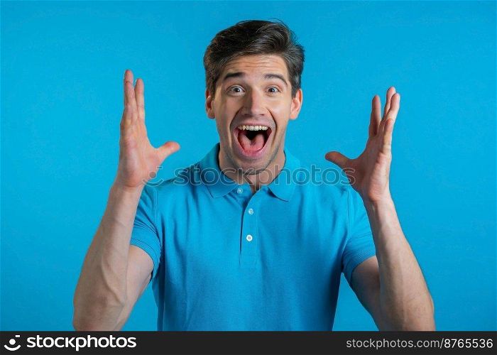 Man depicts amazement, shows WOW delight face effect. Surprised excited happy guy. Handsome male shocked model on blue background. Man depicts amazement, shows WOW delight face effect. Surprised excited happy guy. Handsome male shocked model on blue background.