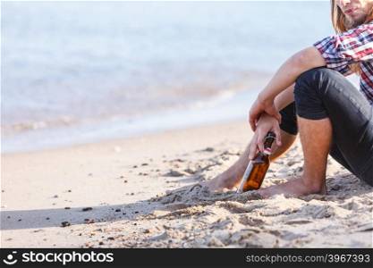 Man depressed with wine bottle sitting on beach outdoor. Man depressed with wine bottle sitting on beach outdoor. People abuse and alcoholism problems