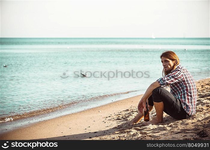 Man depressed with wine bottle sitting on beach outdoor. Man depressed with wine bottle sitting on beach outdoor. People abuse and alcoholism problems