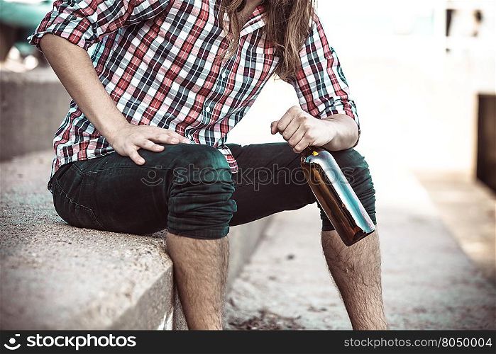 Man depressed with wine bottle sitting on beach outdoor. Man depressed with wine bottle sitting on sea shore outdoor. People abuse and alcoholism problems