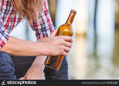 Man depressed with wine bottle sitting on beach outdoor. People abuse and alcoholism problems. Man depressed with wine bottle sitting on beach outdoor