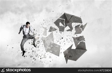 Man destructing recycle symbol. Young dertermined businessman crashing recycle stone symbol