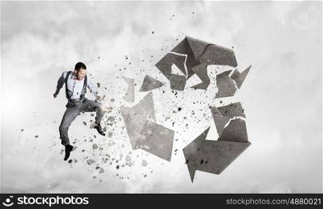 Man destructing recycle symbol. Young dertermined businessman crashing recycle stone symbol