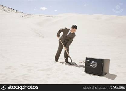 Man digging by safe in desert