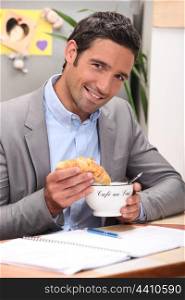 Man dipping croissant into coffee