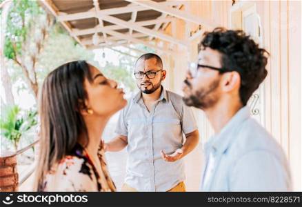 Man discovering his cheating girlfriend kissing another man in the street, Boyfriend discovering his girlfriend&rsquo;s infidelity outdoors. Man looking at his cheating girlfriend kissing another woman outdoors
