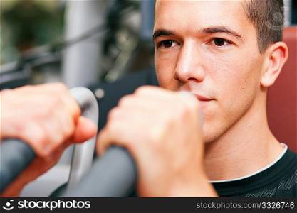 Man doing fitness training on a butterfly machine with weights in a gym