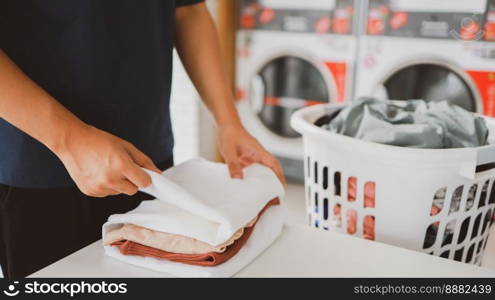 Man doing launder holding basket with dirty laundry of the washing machine in the public store. laundry clothes 