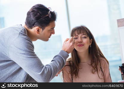 Man doing make-up for cute woman in beauty salon