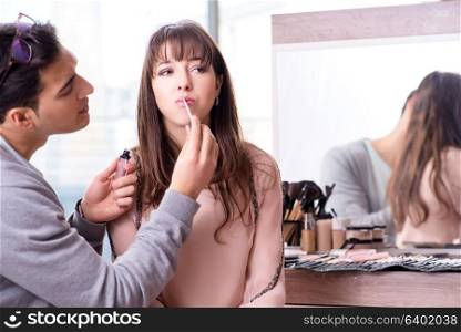 Man doing make-up for cute woman in beauty salon