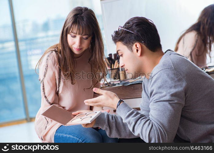 Man doing make-up for cute woman in beauty salon